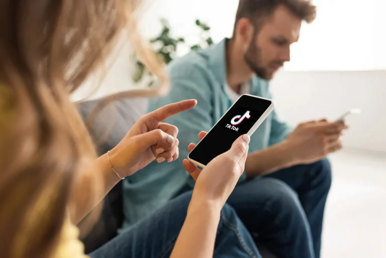 Para ogląda transmisję w aplikacji TikTok — kobieta wskazuje ekran smartfona z logo TikTok
