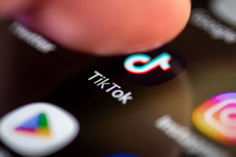 Palec dotyka ikony aplikacji TikTok na ekranie smartfona — śledzenie kliknięć
